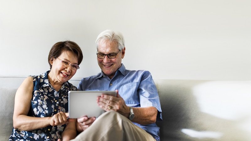 Senior couple using a digital device to check reverse Mortgage